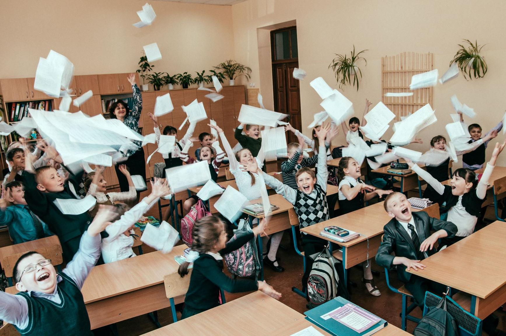 教室里的学生笑着和老师一起把纸扔向空中